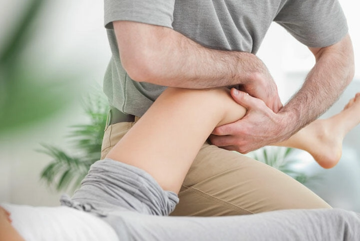 Terapeuta wykonuje masaż nogi pacjenta